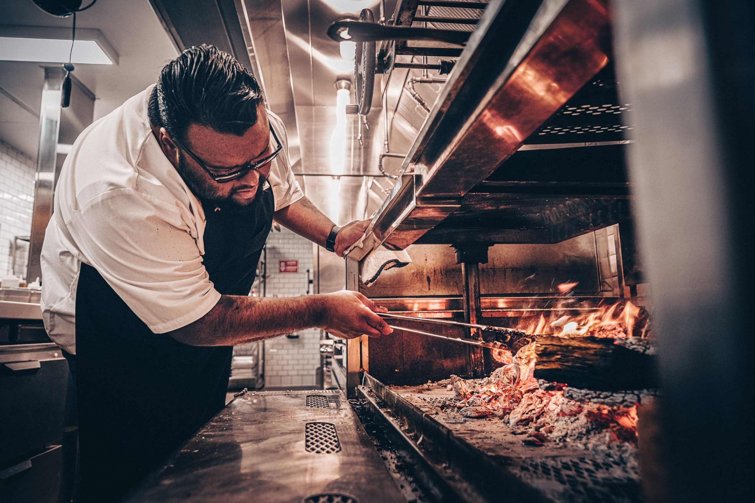 Executive Chef Walter Nunez cooking over wood-fired grill flames at The Rex